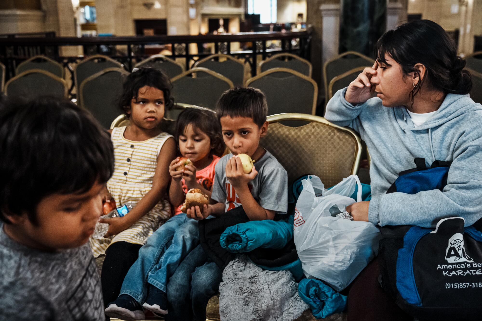 A woman and four children are sitting on chairs.