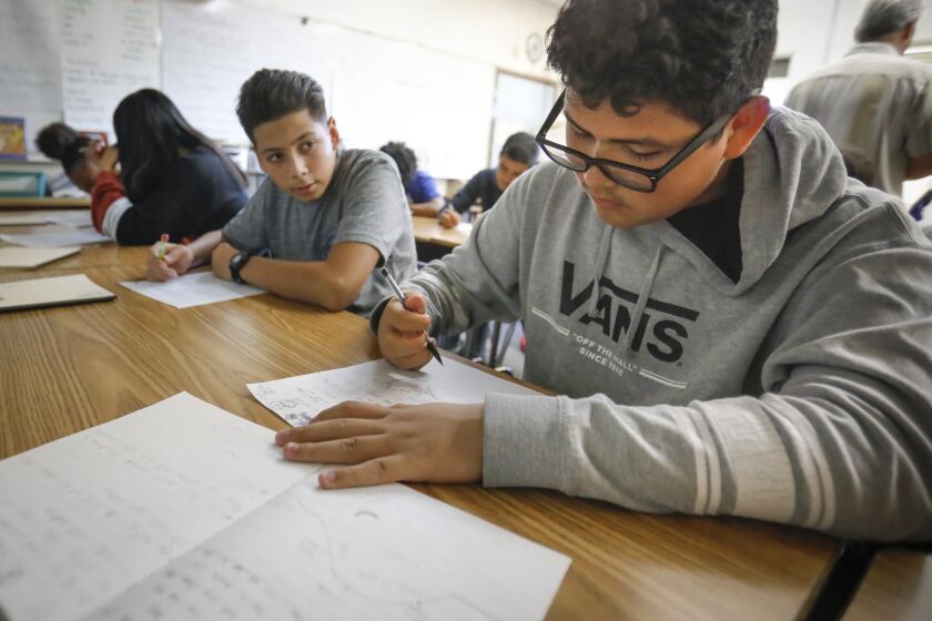 Eighth grade student, Domanick Castro, center, looks on, as he and fellow eighth grader, Jonnie Gallardo, right, students in Glenn Lloyd's English Language Arts class at Wilson Middle School in City Heights, along with other students do a class lesson. Eighth graders in the San Diego Unified School District had more growth on their national test scores than any other urban school district that participated in the national test.