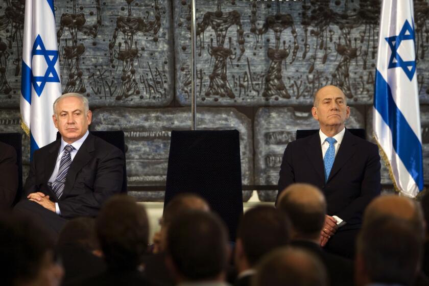 FILE - Outgoing Prime Minister Ehud Olmert, right, sits with new Israeli Prime Minister Benjamin Netanyahu during a handover ceremony at the president's residence in Jerusalem, Wednesday, April 1, 2009. An Israeli court ruled Monday that former Israeli prime minister Ehud Olmert defamed his successor, Benjamin Netanyahu, and ordered him to pay damages to the former leader and his family. (AP Photo/Menahem Kahana, Pool)