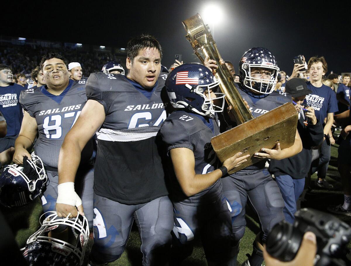Newport Harbor's David Flores (64), Noe Avalos (27), and Aidan Bertonneau (52), celebrate with the rivalry trophy.
