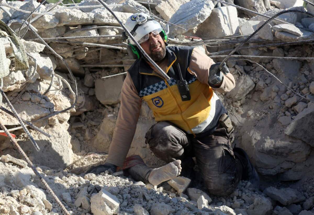 A member of the White Helmets volunteer group prepares to remove the body of a woman killed during shelling and airstrikes on the village of Rakaya Sijneh, in Idlib province, on Saturday.