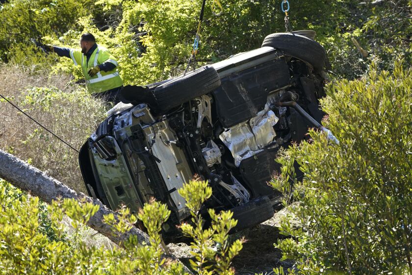 Workers move a vehicle on its side after a rollover accident involving golfer Tiger Woods Tuesday, Feb. 23, 2021, in Rancho Palos Verdes, Calif., a suburb of Los Angeles.. Woods suffered leg injuries in the one-car accident and was undergoing surgery, authorities and his manager said. (AP Photo/Marcio Jose Sanchez)