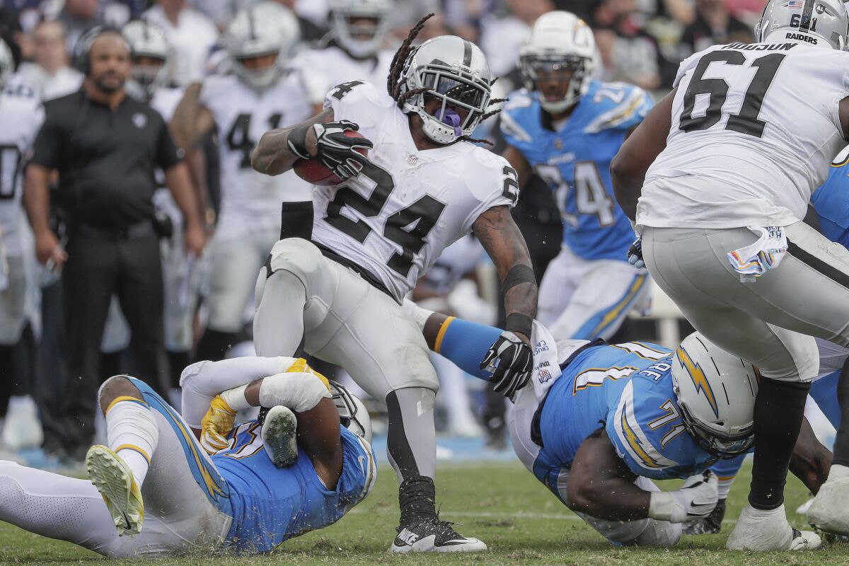 Chargers safety Adrian Phillips, left, and defensive lineman Damion Square stop Oakland Raiders running back Marshawn Lynch for a short gain at StubHub Center during a game earlier this season.