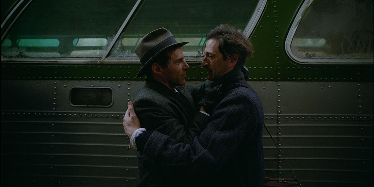 Two men embrace next to a bus.