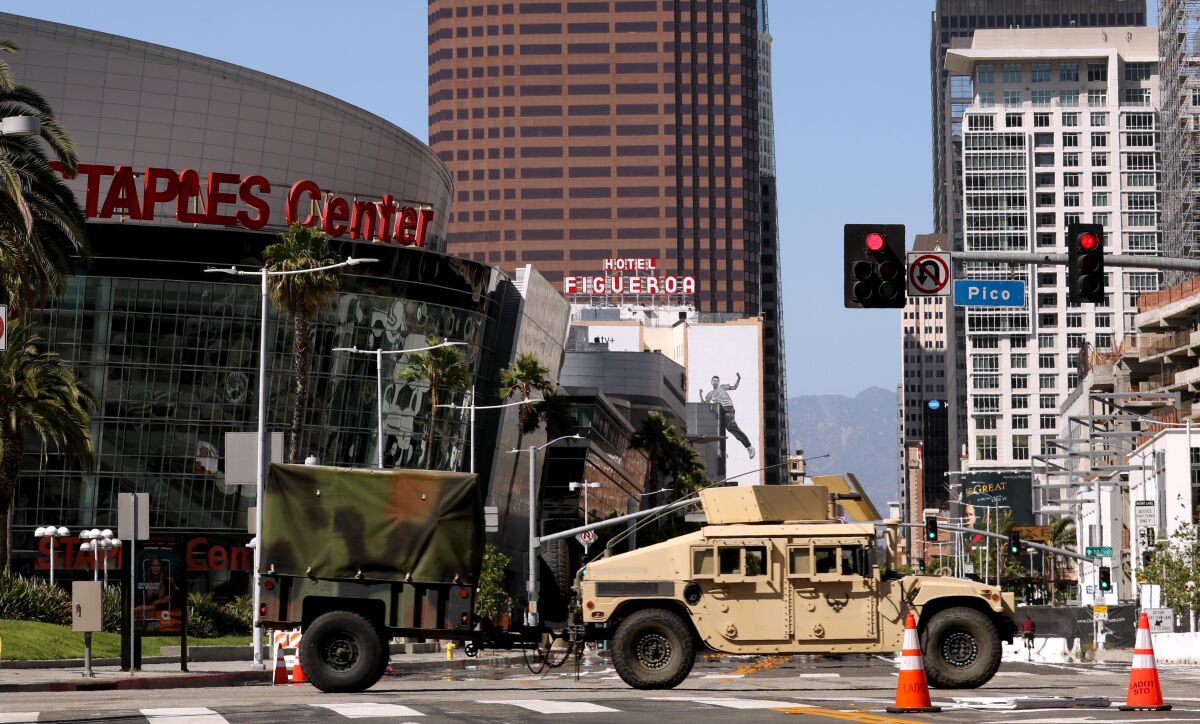 A military vehicle crosses Figueroa Street on Sunday as California National Guardsmen leave the Convention Center in L.A.