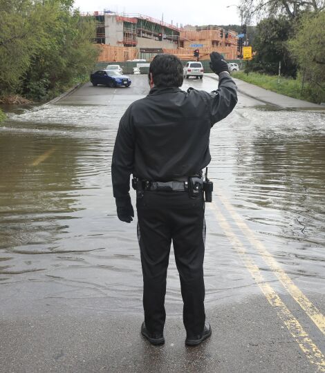 A security guard prevents drivers from attempting to cross flooding over Avenida Del Rio in Mission Valley.