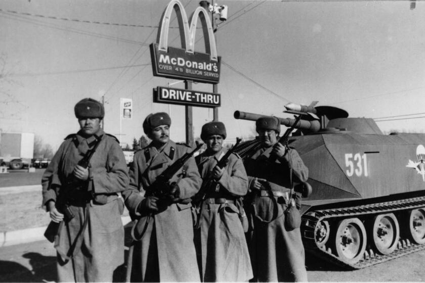 A black and white movie still from "Red Dawn" shows Soviet troops standing before a McDonald's