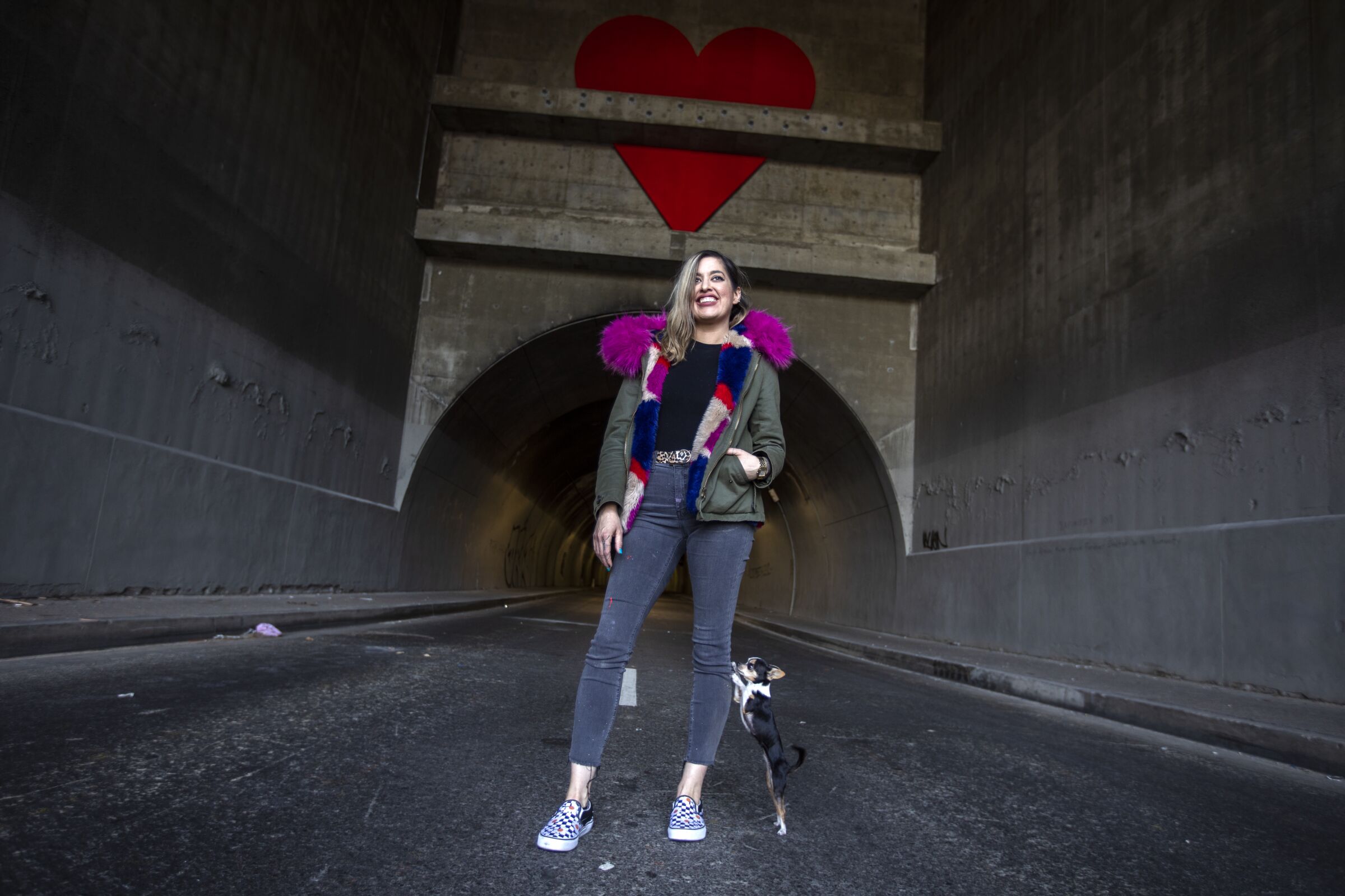 A woman stands in the road with her chihuahua at one end of the 3rd Street Tunnel.