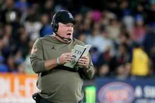 UCLA coach Chip Kelly looks at his play card and shouts on the sideline during the Bruins' loss to Arizona State 