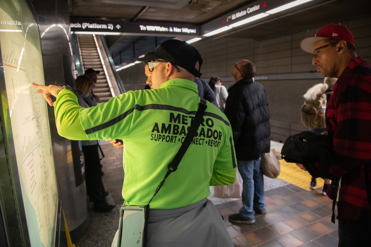A person points on a lighted board while another person watches.