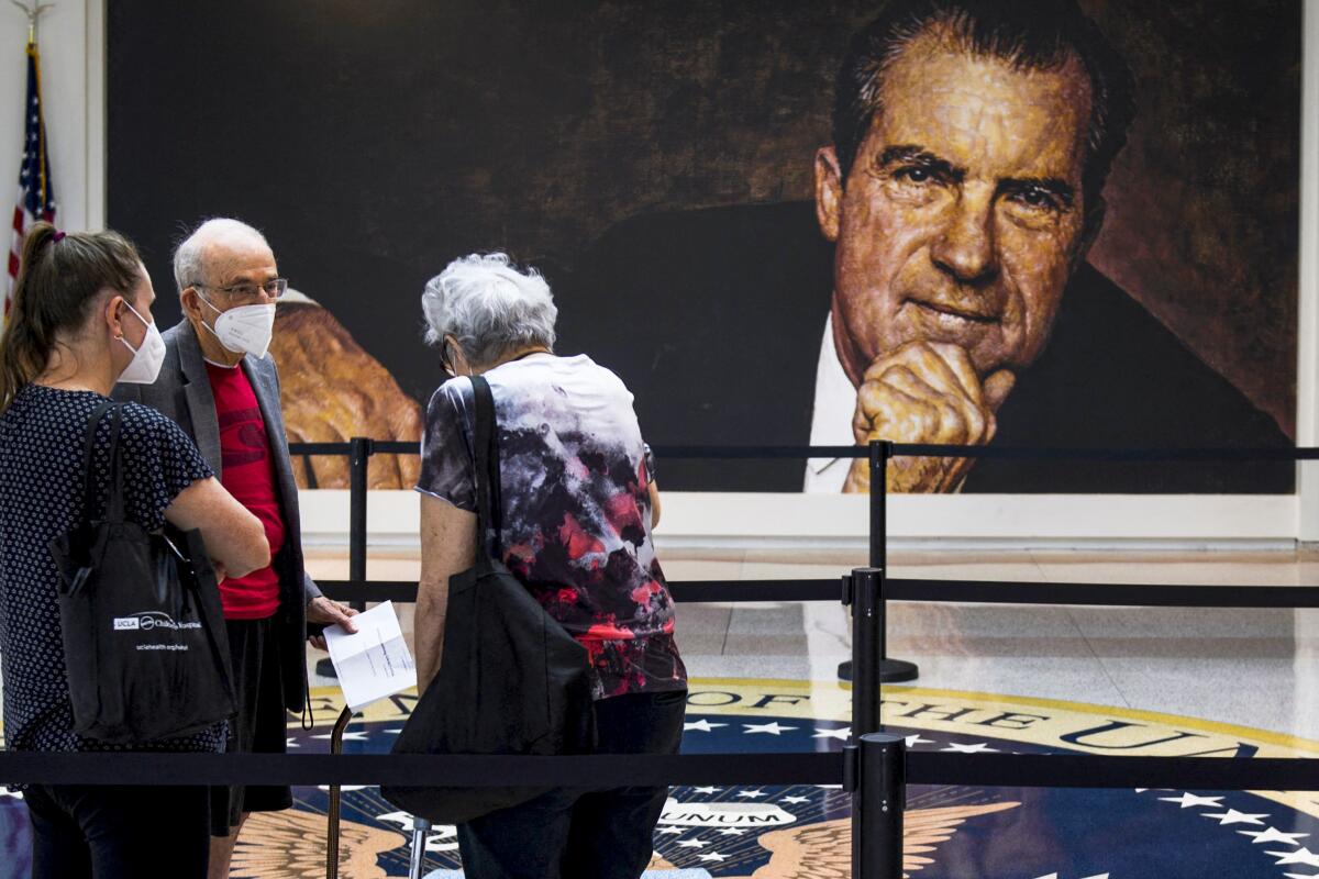 Visitors wait in front of a portrait of former President Nixon at the Nixon Library