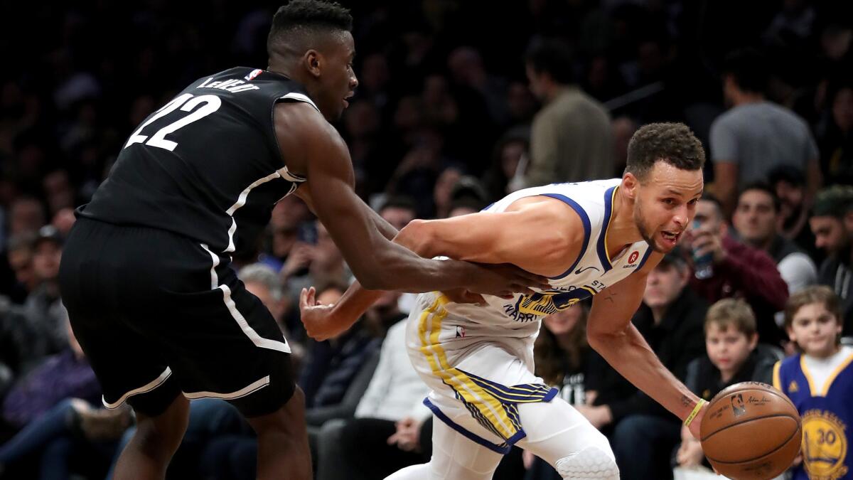 Warriors guard Stephen Curry drives past Nets guard Caris LeVert during the second half Sunday.