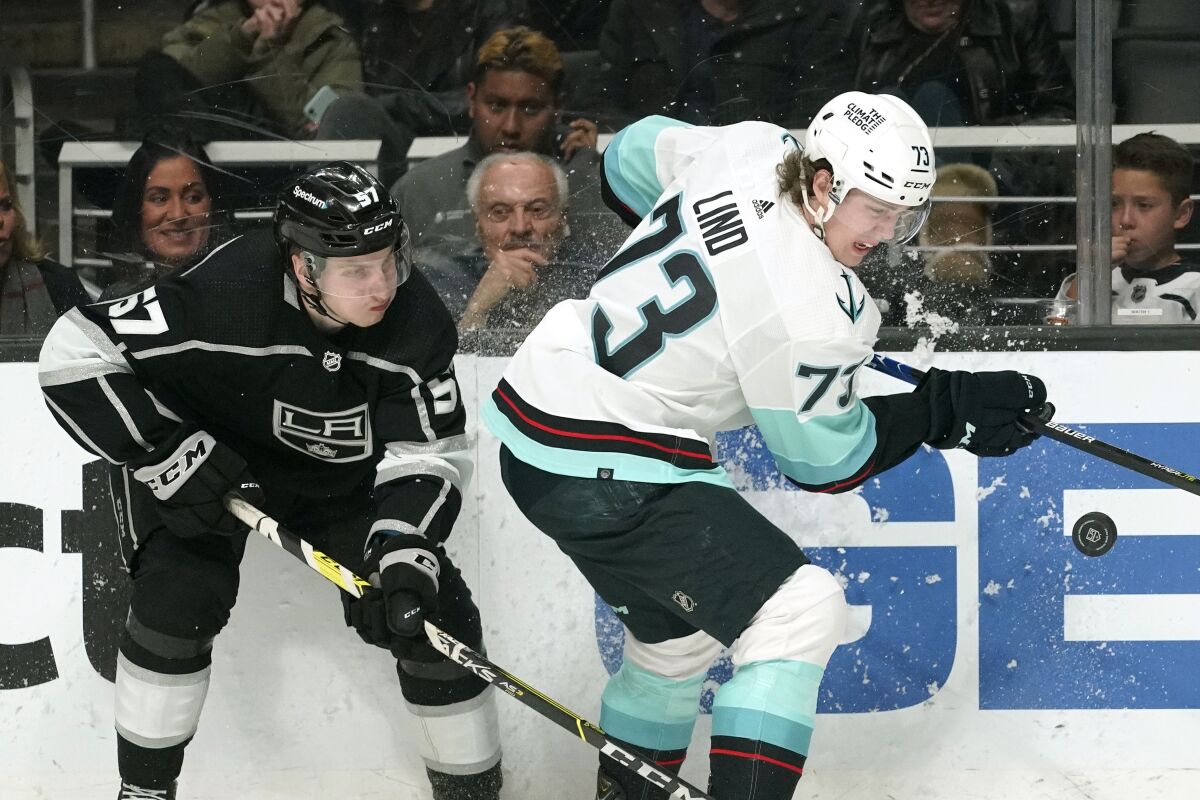 Kings defenseman Jacob Moverare and Seattle Kraken right wing Kole Lind battle for the puck.