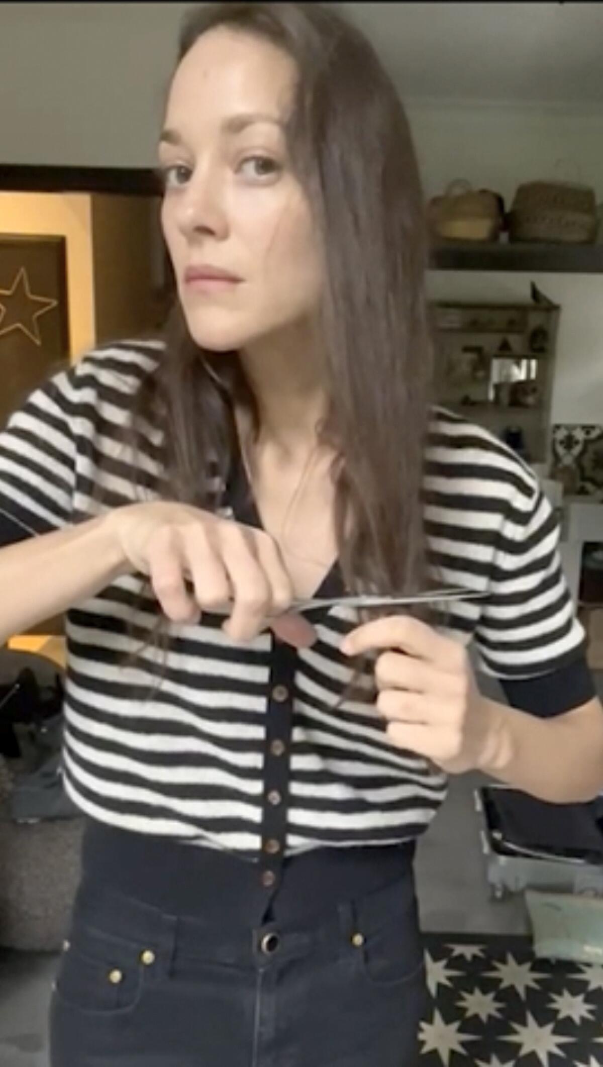 In this image taken from video, Oscar-winning actress Marion Cotillard chops off a lock of her hair to support Iranian protesters standing up to their leadership over the death of Mahsa Amini. Amini, a 22-year-old woman who died in Iran while in police custody, was arrested by Iran's morality police for allegedly violating its strictly-enforced dress code.