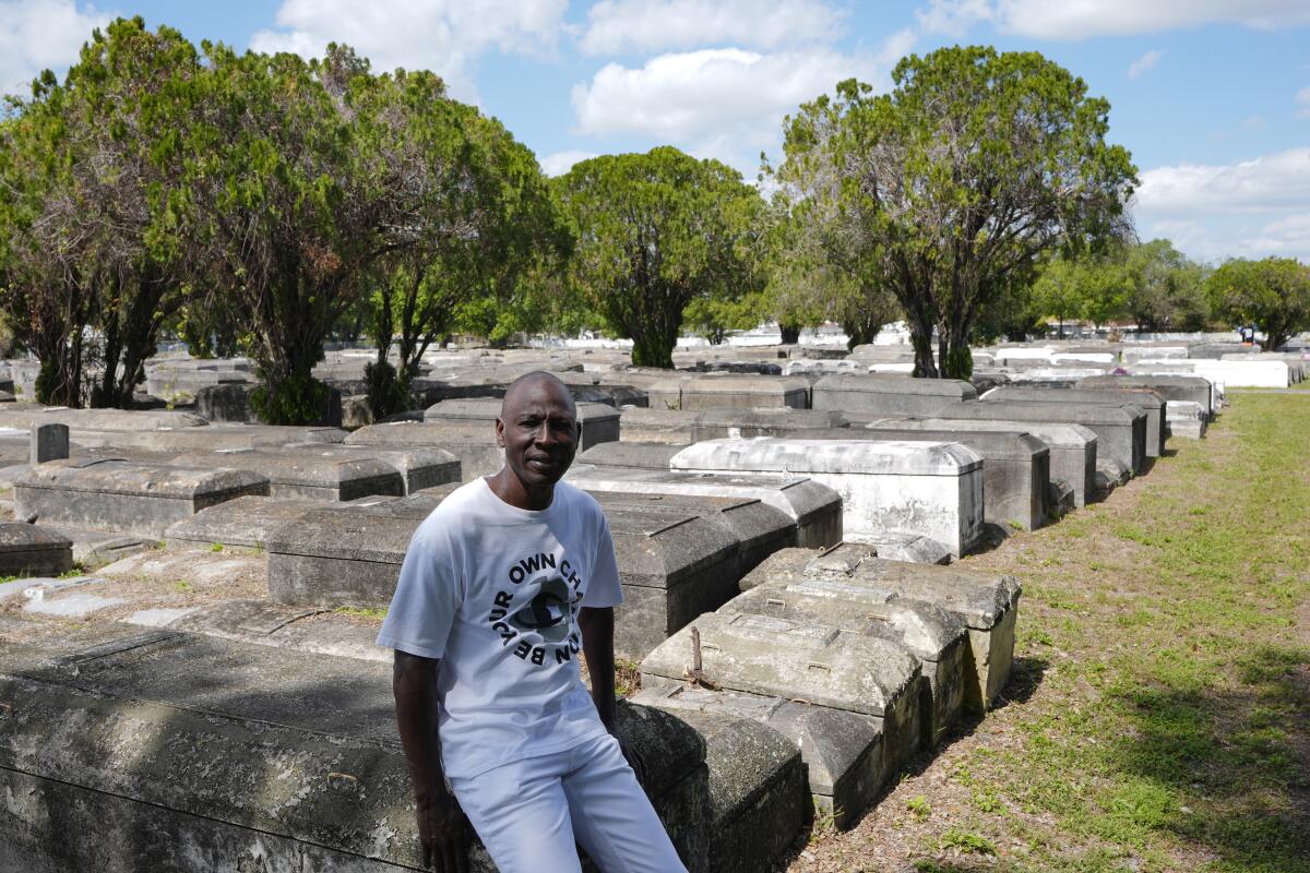 A man sits on a crypt in a cemetery in Florida. 