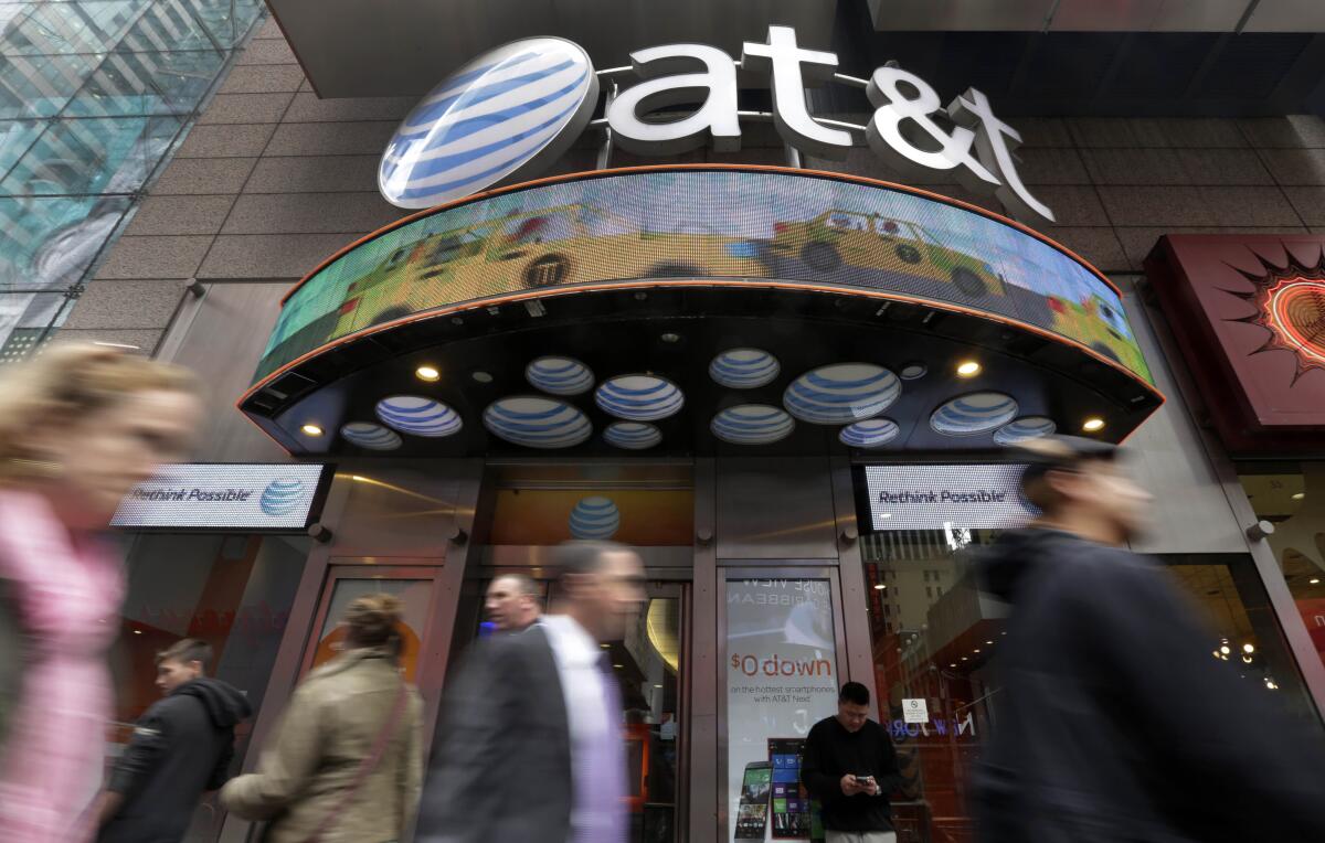 FILE - In this Oct. 21, 2014 file photo, people pass an AT&T store in New York's Times Square. Shares of the new Warner Bros. Discovery media giant, the $43 billion combination of Discovery and the AT&T spinoff WarnerMedia, have begun trading Monday, April 11, 2022. (AP Photo/Richard Drew, File)