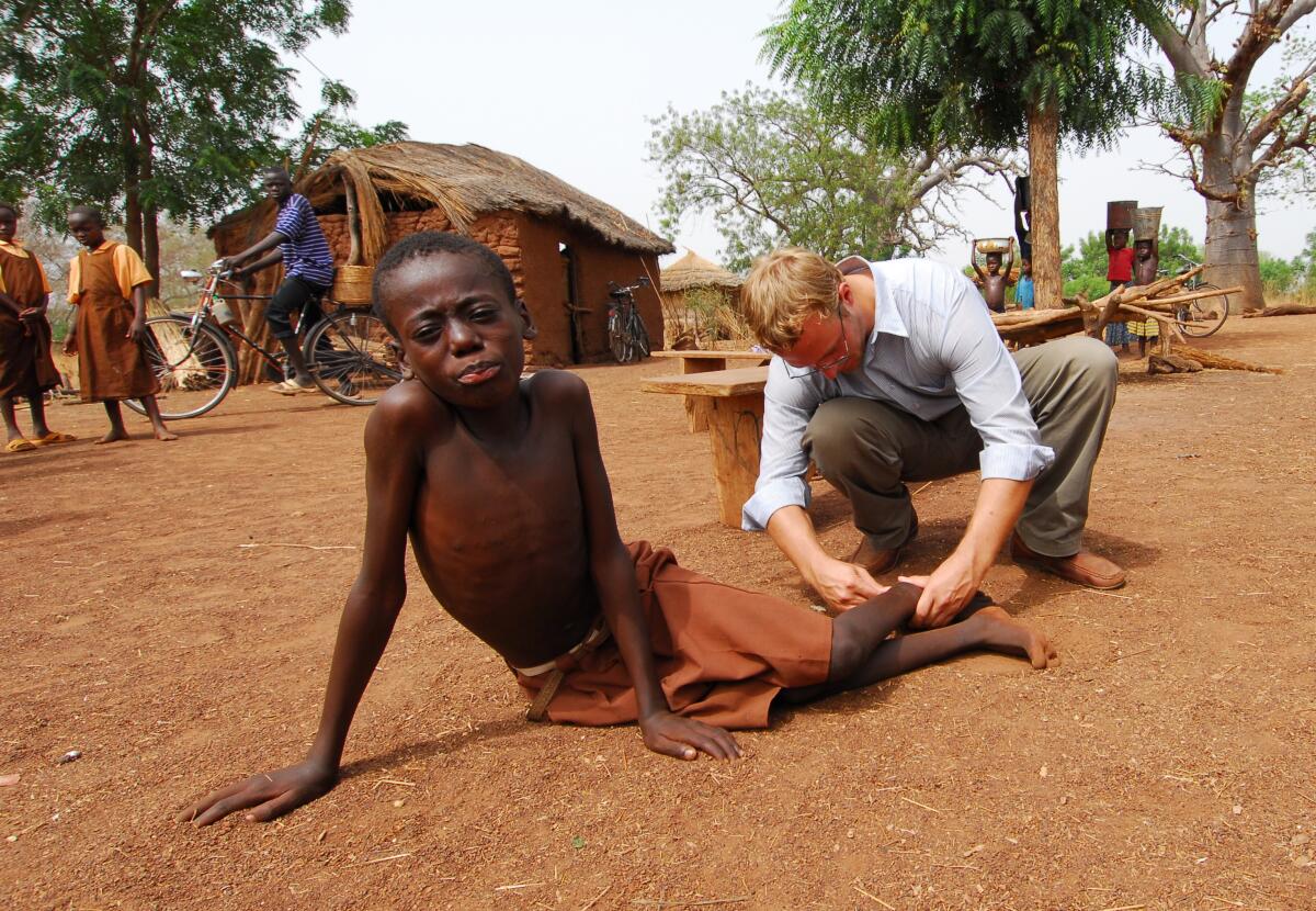 A boy leaning on his arms as a man inspects his leg