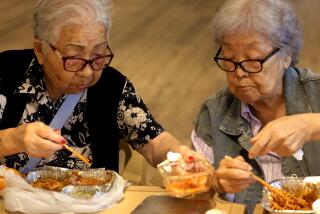 LOS ANGELES, CA - AUGUST 23, 2024 - Jaeyoung Choy, 94, left, and Myung Hong, 88, enjoy a meal, provided by the non-profit group Little Tokyo Senior Nutrition Services (LTNS), at the Little Tokyo Towers in Los Angeles on August 23, 2024. The LTNS delivers free meals to 130 seniors Monday through Friday. For some, it is the only meal the seniors will have for the day. The meals are made at Far Bar, a gastro pub in Little Tokyo. (Genaro Molina/Los Angeles Times)