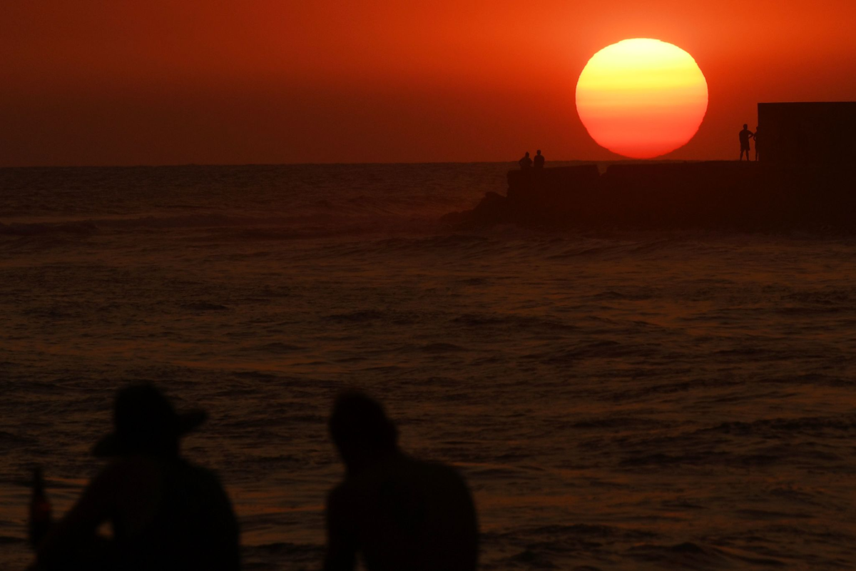 Silhouettes are seen on a beach at sunset.