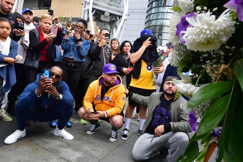 People gather around a makeshift memorial for former NBA and Los Angeles Lakers player Kobe Bryant after learning of his death at LA Live plaza in front of Staples Center in Los Angeles on January 26, 2020. - NBA legend Kobe Bryant died January 26, 2020 in a helicopter crash in suburban Los Angeles, celebrity website TMZ reported, saying five people are confirmed dead in the incident. (Photo by Frederic J. Brown / AFP) (Photo by FREDERIC J. BROWN/AFP via Getty Images)