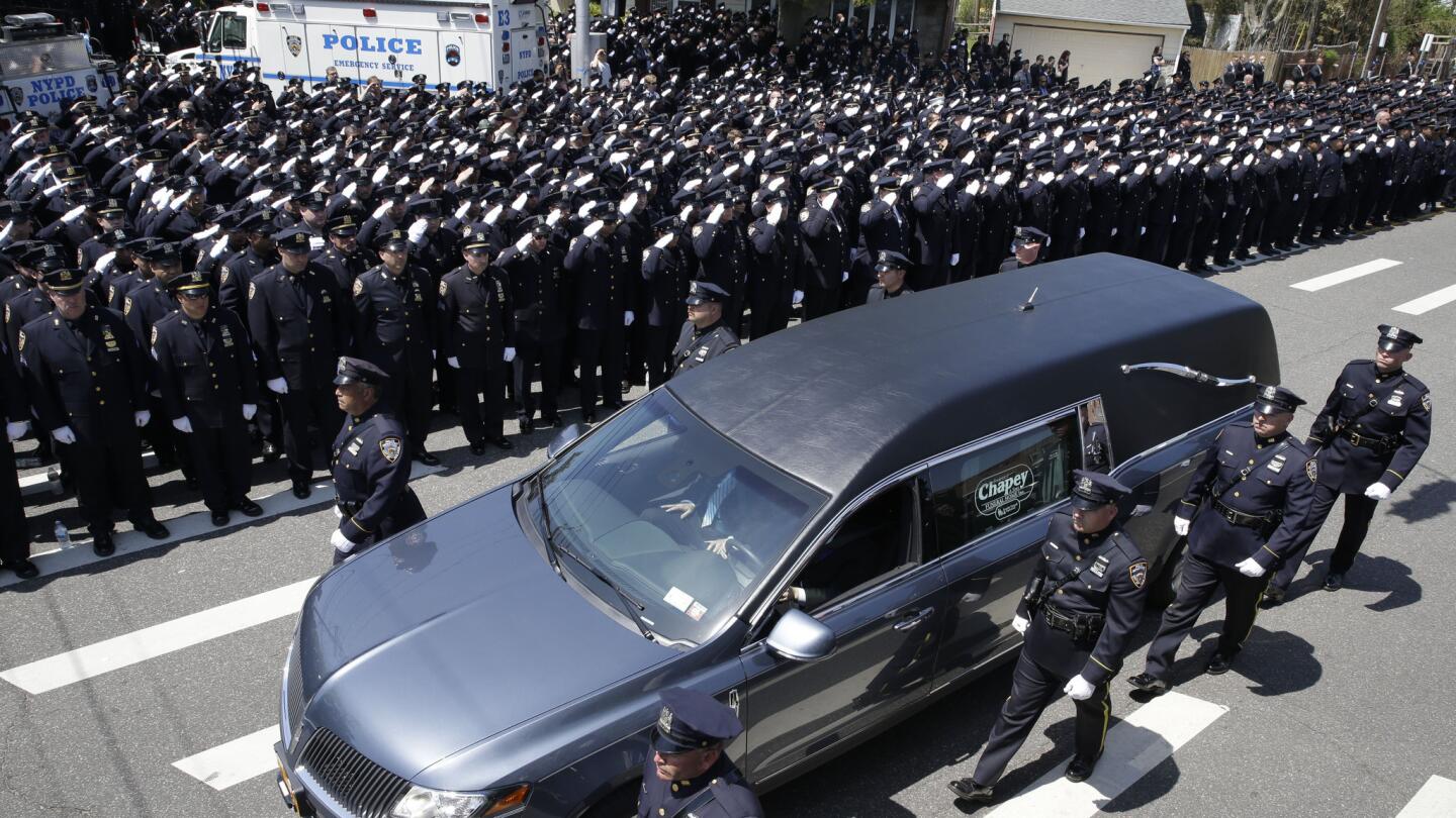 Police officers salute as the procession for New York City police Officer Brian Moore passes after his funeral Mass on Friday, May 8, 2015, at St. James Roman Catholic church in Seaford, N.Y. The 25-year-old died Monday, two days after he was shot in Queens.