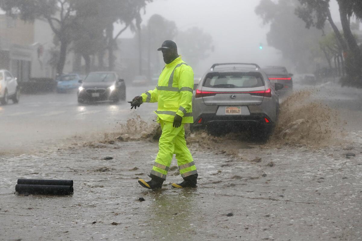 A city worker in the public works department picks up debris carried onto the highway from a heavy rainfall.