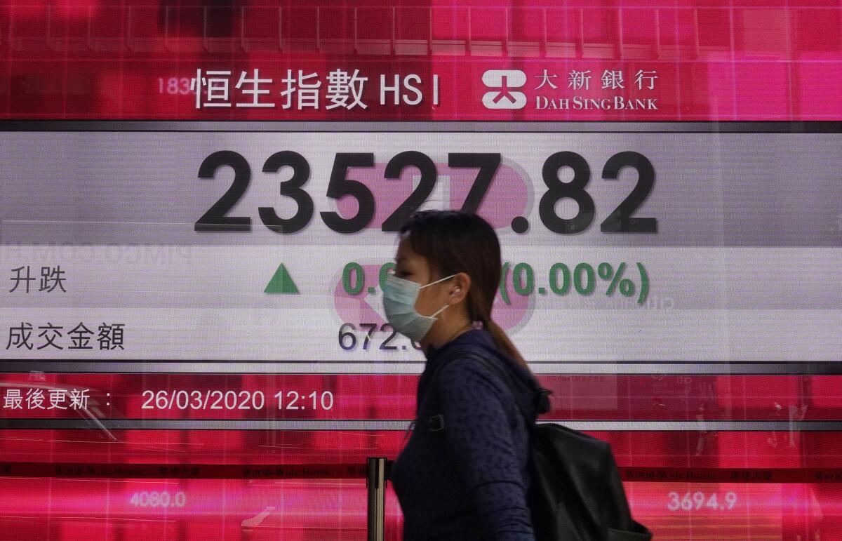 A woman walks past an electronic board at the Hong Kong Stock Exchange on March 26.