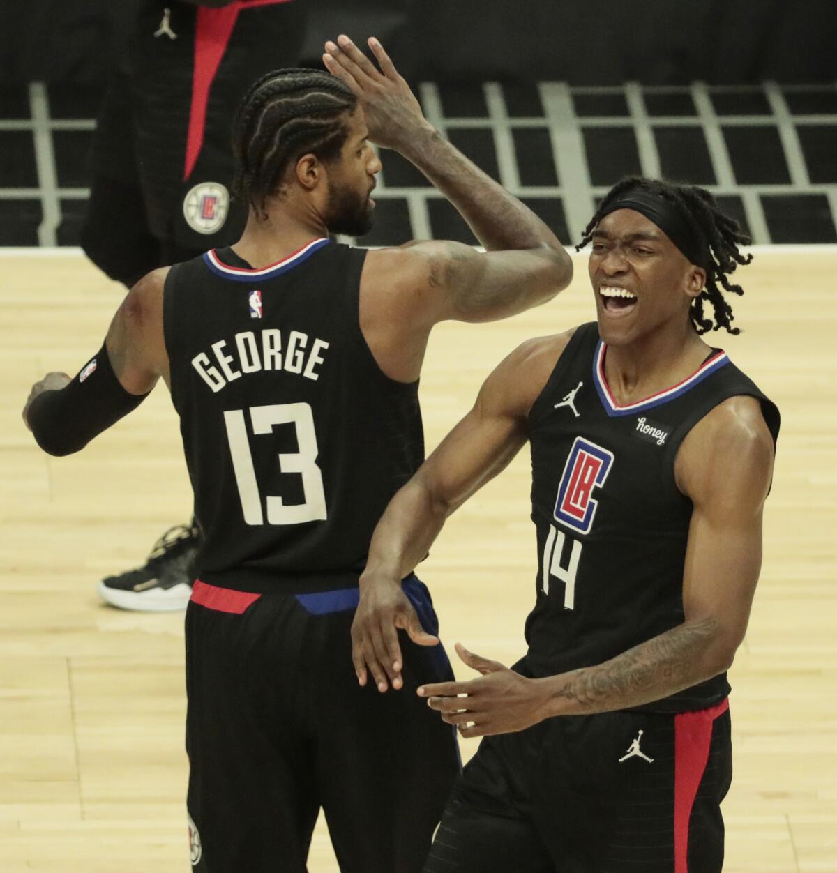 Clippers guard Terance Mann #14 celebrates with teammate Paul George after getting fouled while making a layup.