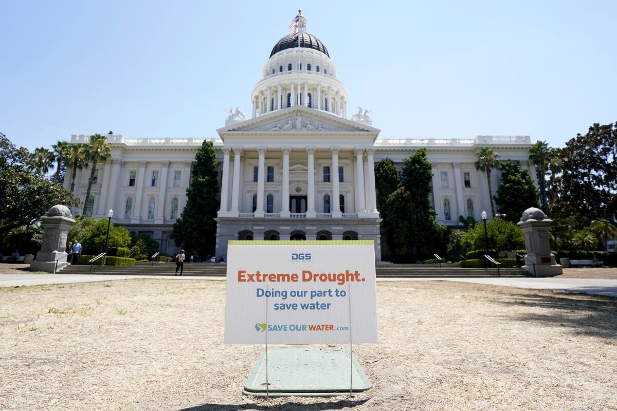 A sign posted on browning grass outside the state Capitol notes watering restrictions because of extreme drought.