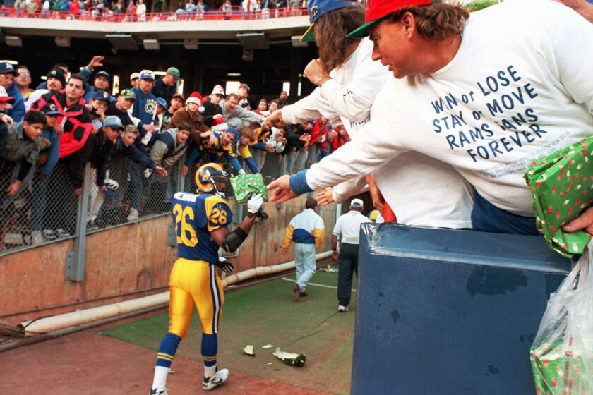 A Los Angeles Rams fan, wearing his sentiments on his shirt, hands safety Anthony Newman a gift after a game against the Redskins on Dec. 24, 1994 in Anaheim, Calif.