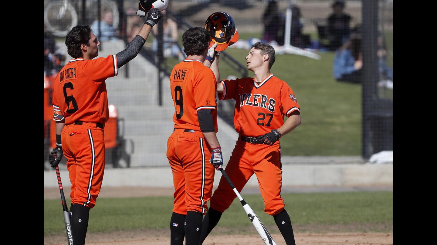 Huntington Beach High's Jake Vogel, right, taps helmets with teammates Josh Hahn, center, and Brett Barrera, left, as they congratulate him on a two-run homer against Fountain Valley during the first inning in a Surf League game at Huntington Beach High on Friday, March 15, 2019.
