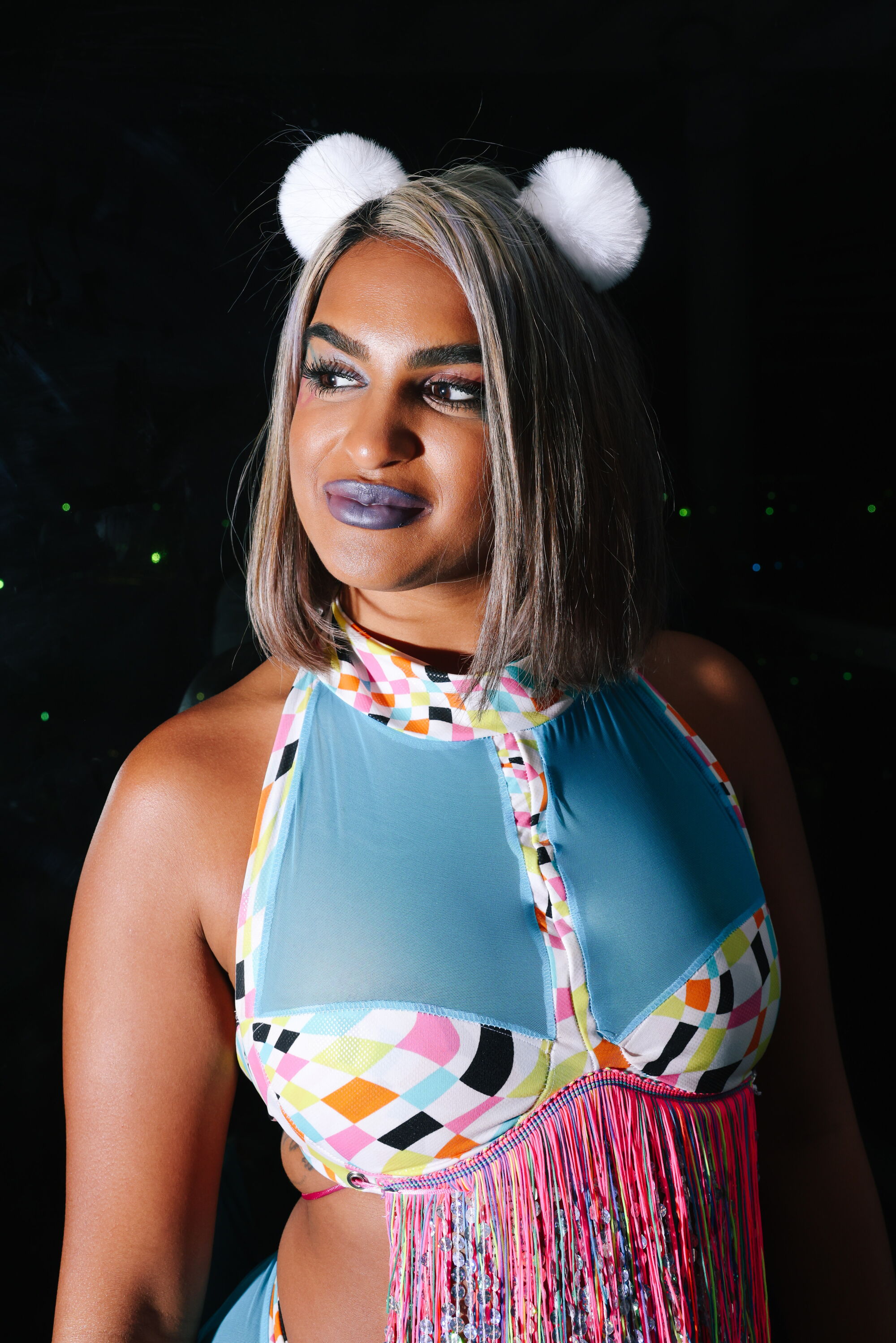 Close up of a woman wearing a blue mesh halter with two pom poms sticking up from her head