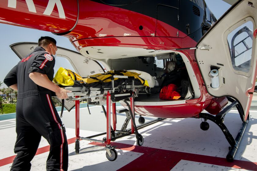 Jason Nguyen, a flight nurse with REACH Air Medical Services operating under call sign Reach 9, loads an El Centro Regional Medical Center patient aboard an air ambulance bound for a San Diego area hospital on May 20, 2020 in El Centro, California. A weekend surge of COVID patients forced the hospital to transfer 27 patients to other hospitals in one 24-hour period from Tuesday afternoon through Wednesday morning.