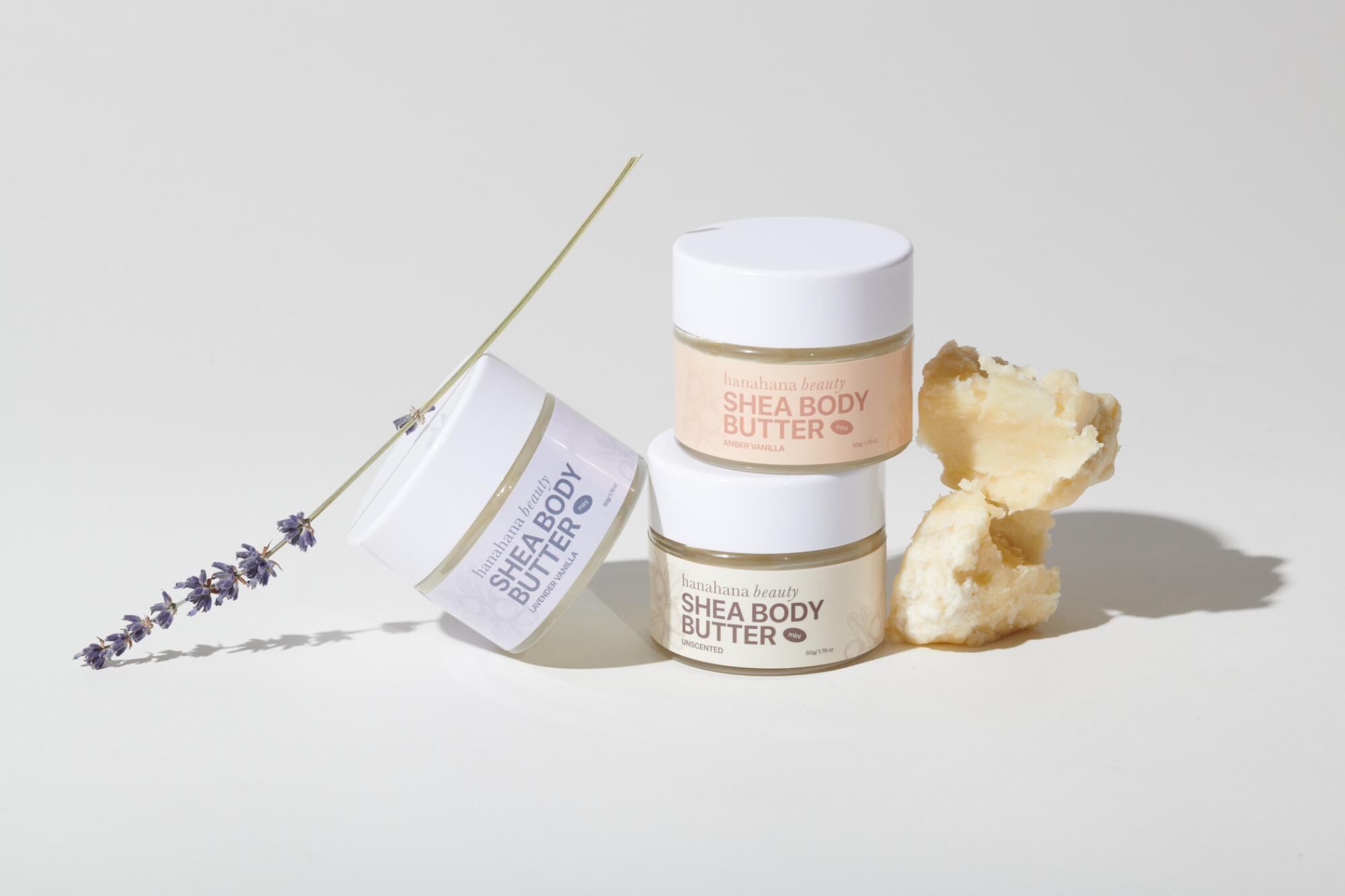 Three jars of Hanahana Beauty Shea Body Butter with a sprig of lavender