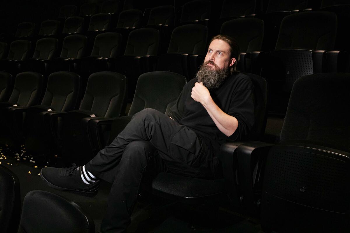 A man in black is seated in a movie theater.