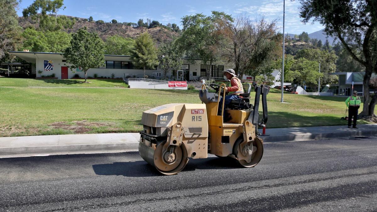 Construction workers install rubberized asphalt on Knight Way in front of Paradise Canyon Elementary School on Tuesday. Nine hundred linear feet of the street was covered with new asphalt and 1,100 linear feet of asphalt on Gould Avenue was also replaced.