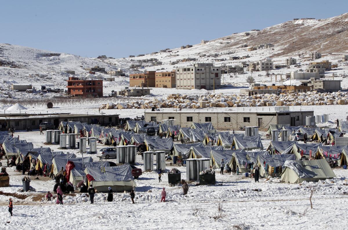 Syrian refugees walk outside their tents at a camp in the Lebanese town of Arsal.