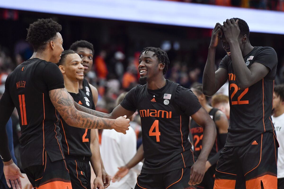 Miami guard Jordan Miller, left, guard Bensley Joseph (4) and forward Deng Gak (22) celebrate their win against Syracuse after an NCAA college basketball game in Syracuse, N.Y., Saturday, March 5, 2022. (AP Photo/Adrian Kraus)