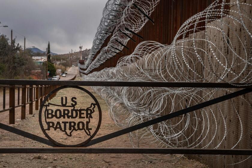 Una cerca de metal marcada con el signo de la Patrulla Fronteriza de los EE. UU. evita que las personas se acerquen al alambre de púas, concertina, que cubre la cerca de la frontera de los EE. UU. y México, en Nogales, Arizona, el 9 de febrero de 2019.