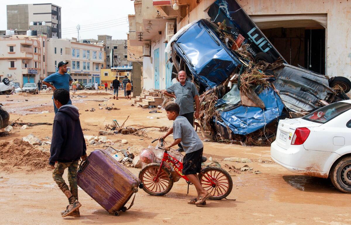 A Libyan boy pulls a suitcase past debris in a flood-damaged area of Derna.