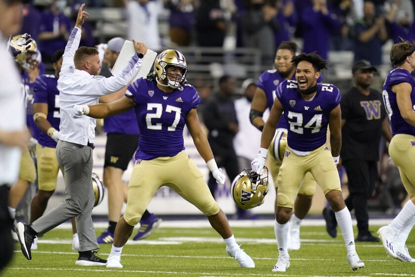Washington players and coaches celebrate beating California on Sept. 25, 2021.