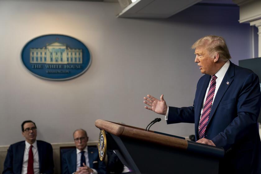 President Donald Trump, accompanied by Treasury Secretary Steven Mnuchin, left, and White House chief economic adviser Larry Kudlow, second from left, speaks at a news conference in the James Brady Press Briefing Room at the White House, Wednesday, Aug. 12, 2020, in Washington. (AP Photo/Andrew Harnik)
