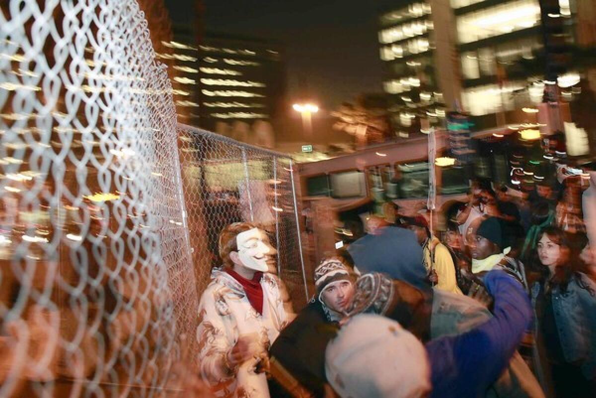 Occupy L.A. members gather near the fence erected around Los Angeles City Hall as they march along Spring Street toward the north steps of City Hall during a protest Wednesday night.