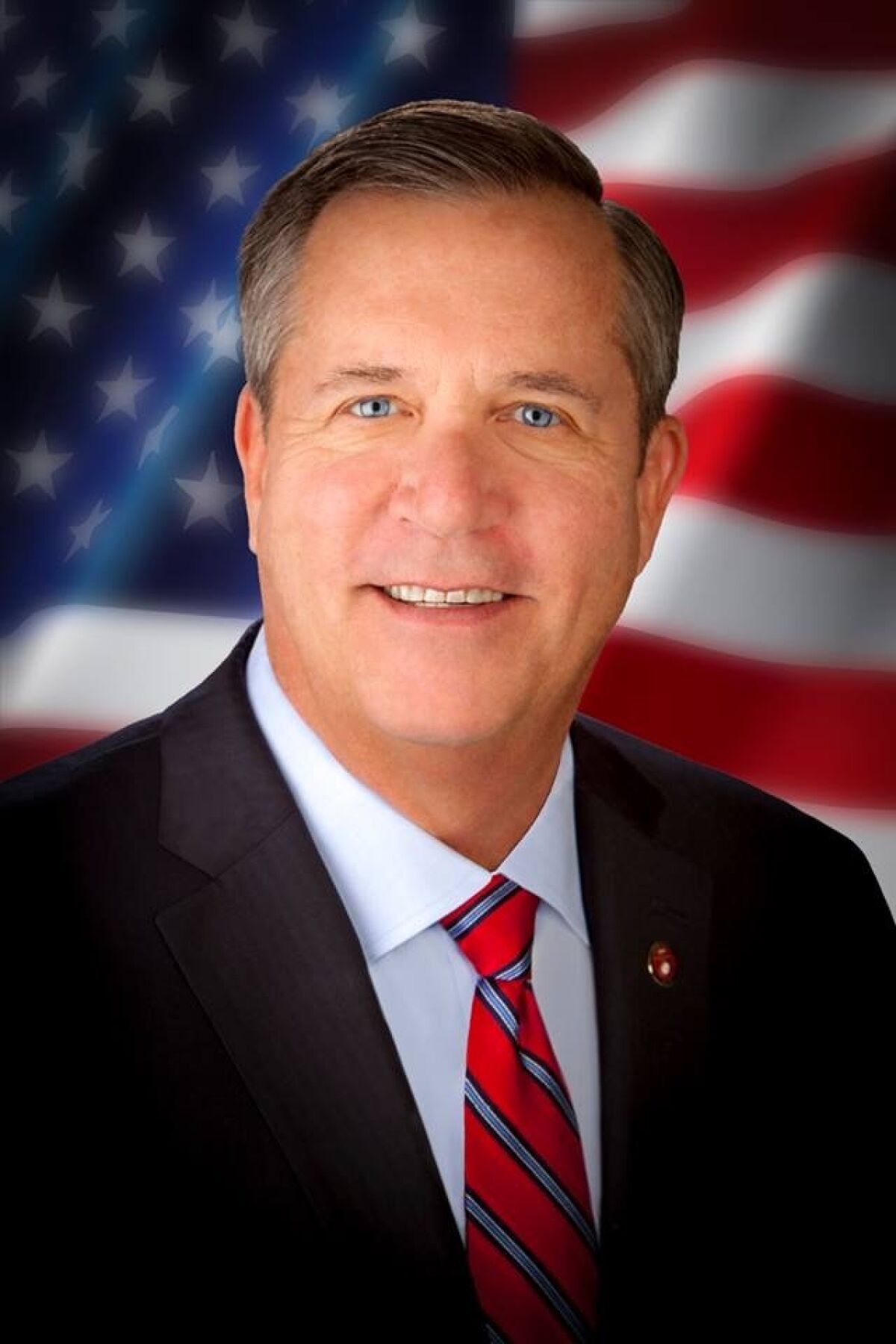A portrait of Mission Viejo Councilman Greg Raths with the American flag as a background