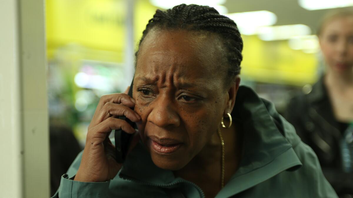 A woman speaks into a cellphone, looking concerned