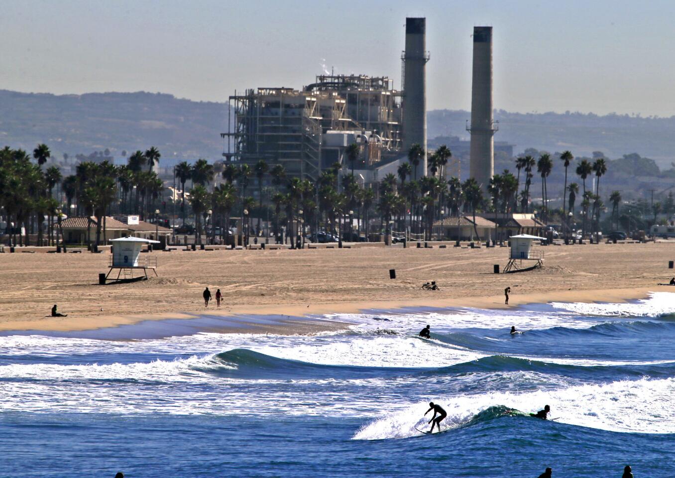 The AES Huntington Beach Generating Station forms a backdrop to surfers enjoying a spring-like November morning. The California Coastal Commission is expected to vote this week on a proposed seawater desalination plant on a portion of the AES site.