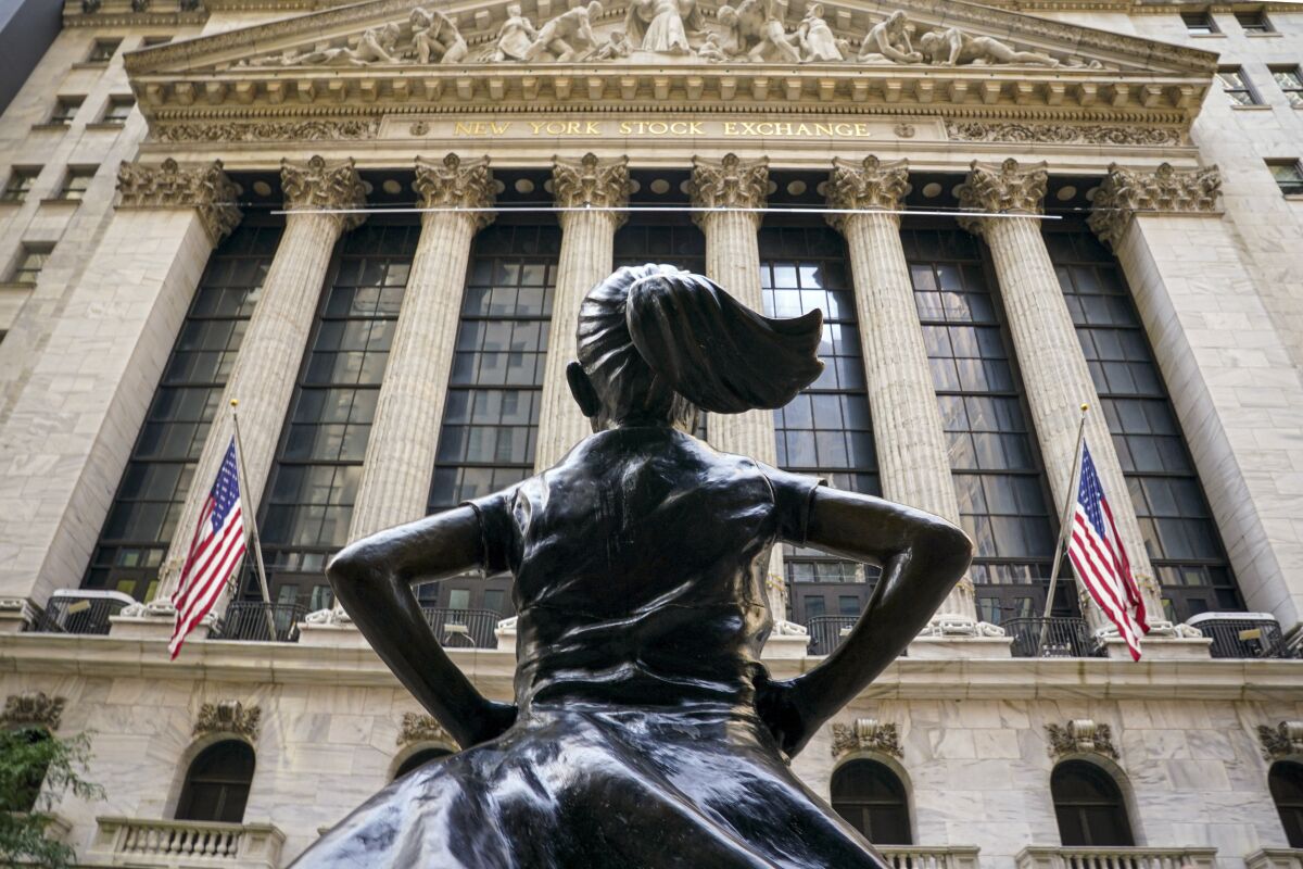 FILE- In this Aug. 25, 2020, file photo, the 'Fearless Girl' bronze sculpture, commissioned by State Street Global Advisors, looks towards the New York Stock Exchange from its roadside perch in New York. Amid the push to get U.S. boardrooms to look more like companies’ customers and employees, advocates are finally seeing just how steep the task will be. Boards of directors at publicly traded U.S. companies are much more white and much less diverse than the overall population, often starkly so. (AP Photo/Bebeto Matthews, File)