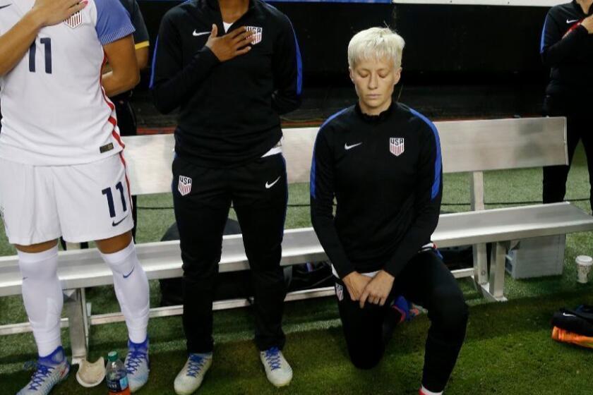 United States midfielder Megan Rapinoe kneels next to teammates as the U.S. national anthem is played before an exhibition soccer match on Sept. 18, 2016.