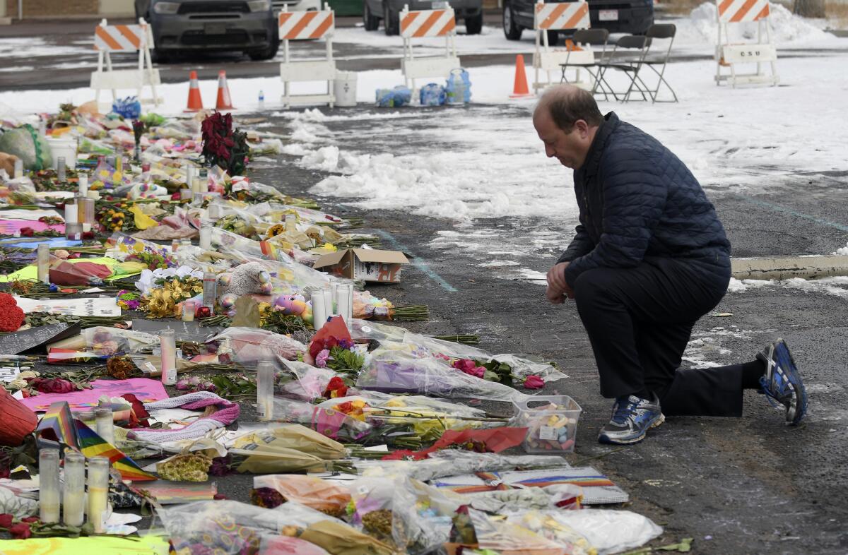 Colorado Gov. Jared Polis kneeling in front of a memorial to shooting victims