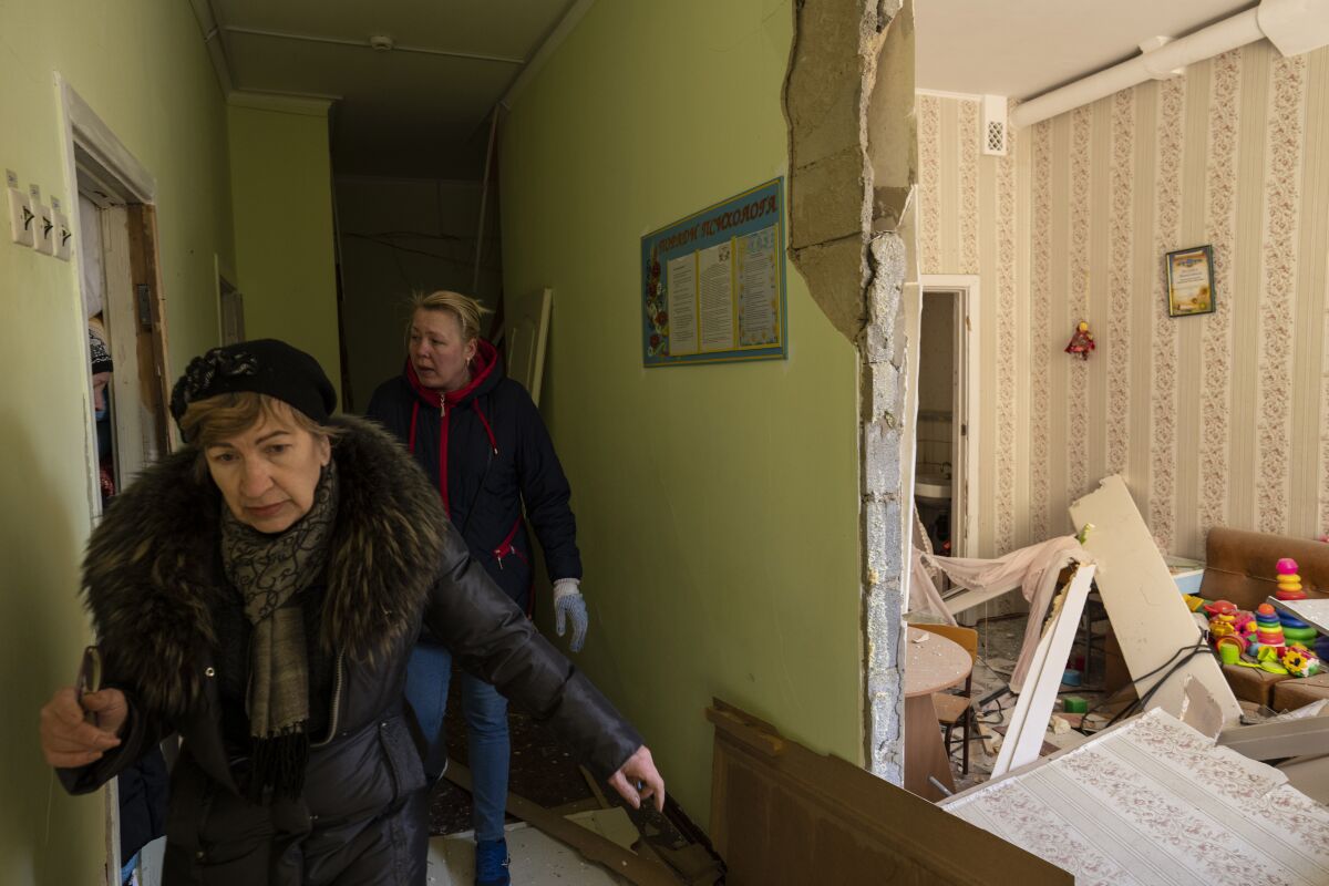 Women walks inside a school damaged among other residential buildings following a bombing in Kyiv, Ukraine, Friday, March 18, 2022. Russian forces pressed their assault on Ukrainian cities Friday, with new missile strikes and shelling on the edges of the capital Kyiv and the western city of Lviv, as world leaders pushed for an investigation of the Kremlin's repeated attacks on civilian targets, including schools, hospitals and residential areas. (AP Photo/Rodrigo Abd)